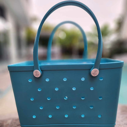 Aqua Marine Silicone Bag: Sustainable Style for Every Adventure. [Eye-catching aqua marine silicone bag pops against a blurred green background, perfect for eco-conscious outings.]