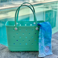 * "Seafoam Eva Silicone bag showing the Swinging Palms Sand Free Hoodie for kids."