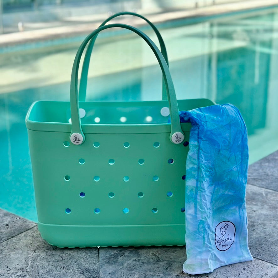 * "Seafoam Eva Silicone bag showing the Swinging Palms Sand Free Hoodie for kids."