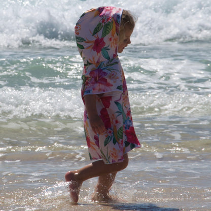 Girl (ages 3-6) wearing an Island Princess hooded beach hoodie (vibrant hibiscus flower design) with the hood pulled up. She is walking and strolling along the beach at Currumbin, Queensland.