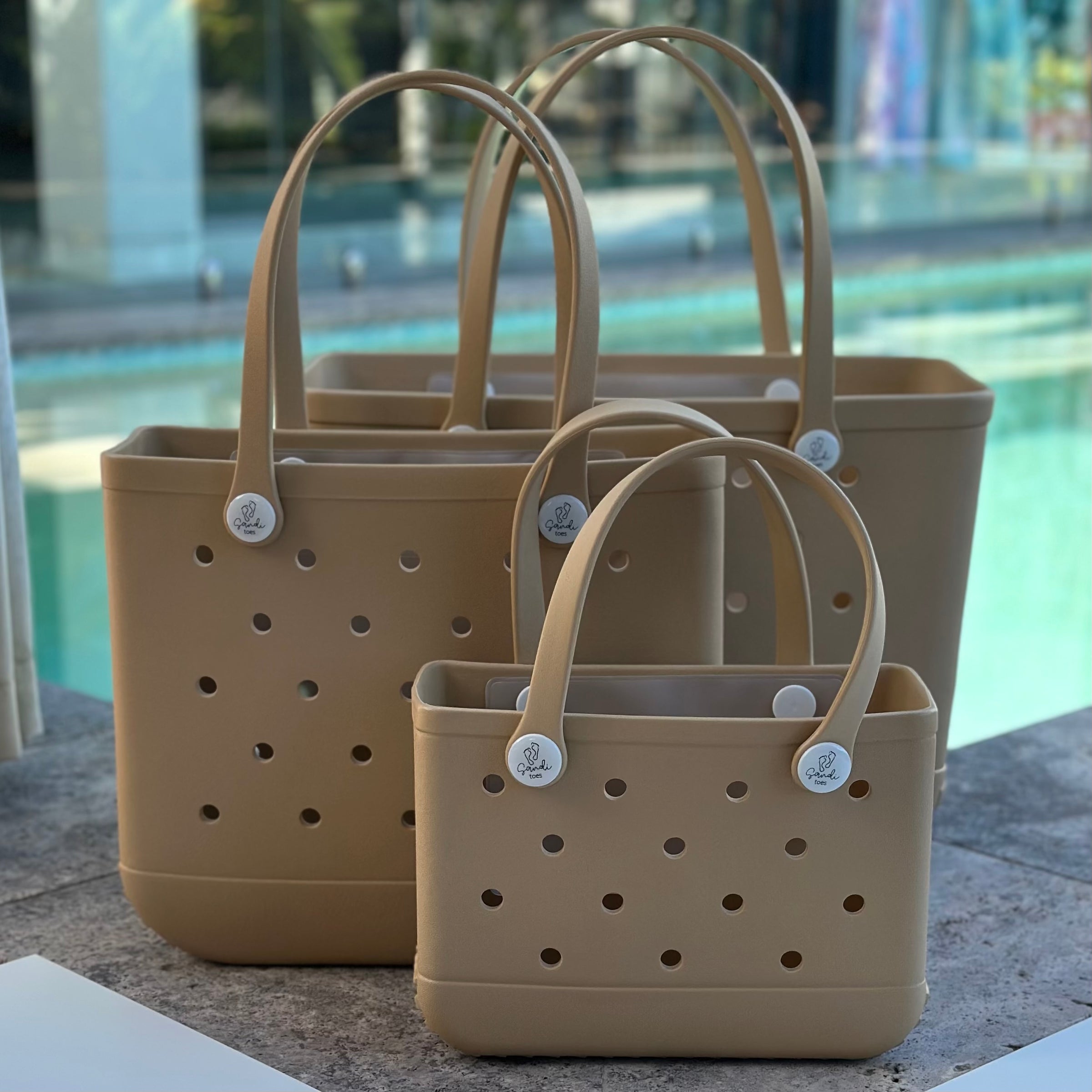 All three Sand EVA silicone beach tote bags front view The Hauler, The Everyday and The Mini, showing size, Sandi Toes buttons, and sturdy handles"