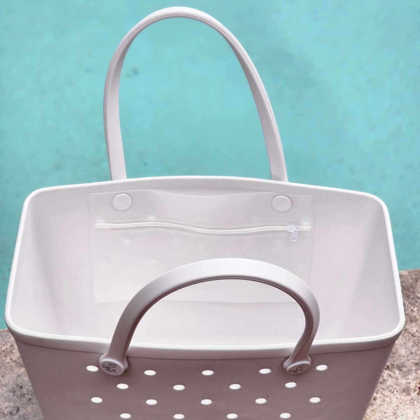 White Haven Silicone Bag (Sandi Toes): Spacious Poolside Organizer. [Open White Haven silicone bag with Sandi Toes logo reveals a large interior, perfect for storing poolside essentials like towels, sunscreen, and drinks.]