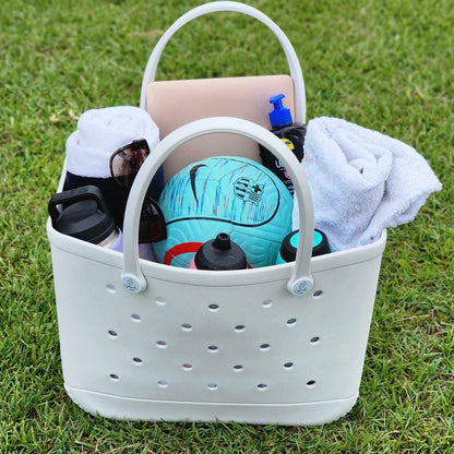 White Haven Silicone Bag (Sandi Toes): Beach Ready for the Whole Crew. [Spacious white silicone bag with the Sandi Toes logo brims with beach essentials - sunglasses, hat, hoodies, water bottles, phone, and even a soccer ball - perfect for a fun-filled day at the beach with friends or family.]