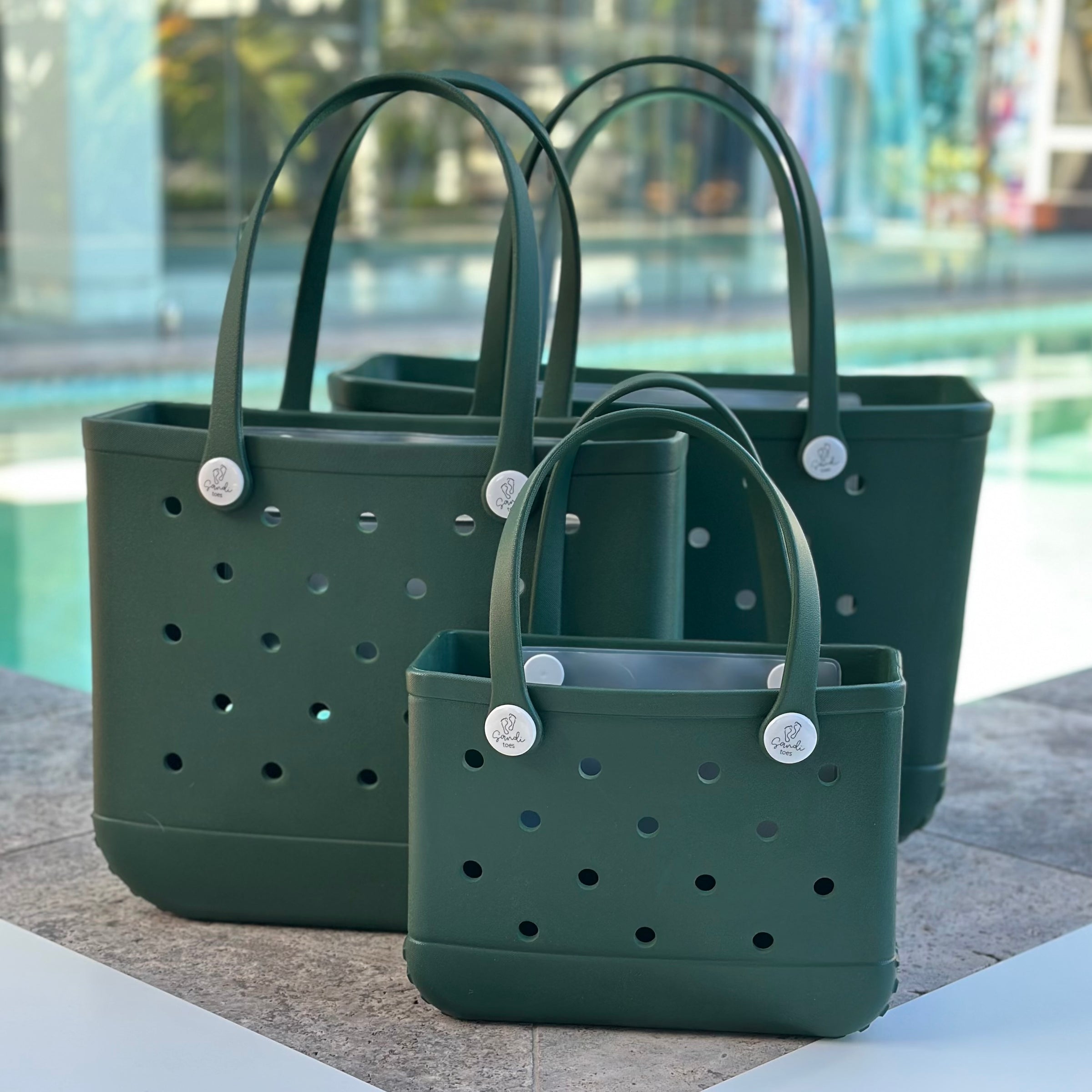 * "All three Sea Moss EVA silicone beach tote bags front view The Hauler, The Everyday and The Mini, showing size, Sandi Toes buttons, and sturdy handles"