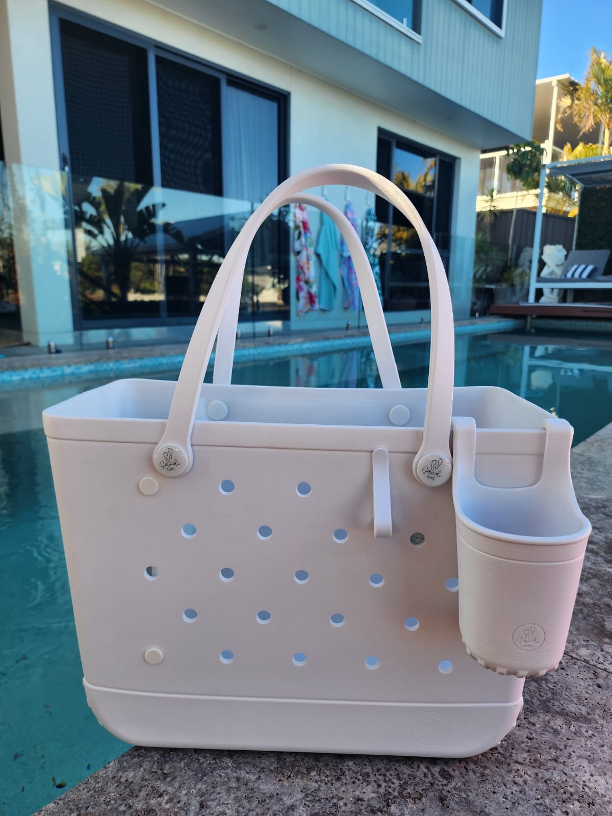White Haven Tote Bag with Silicone Cup holder and key clip beside a swimming pool
