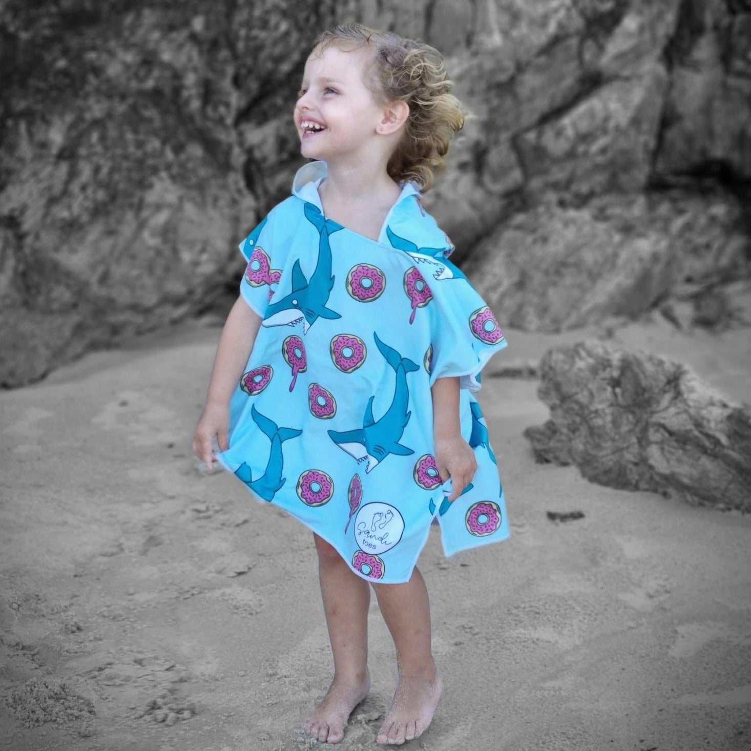 Sand Free Beach Towel shows 3 year old girl at Currumbin Beach Queensland with sharks and donuts on her beach towel big smile