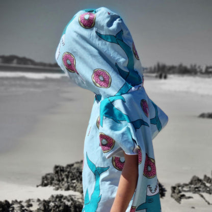 This picture is of a 5 year old boy wearing a sand free beach towel with Feeding Frenzy donuts and sharks on a blue towel
