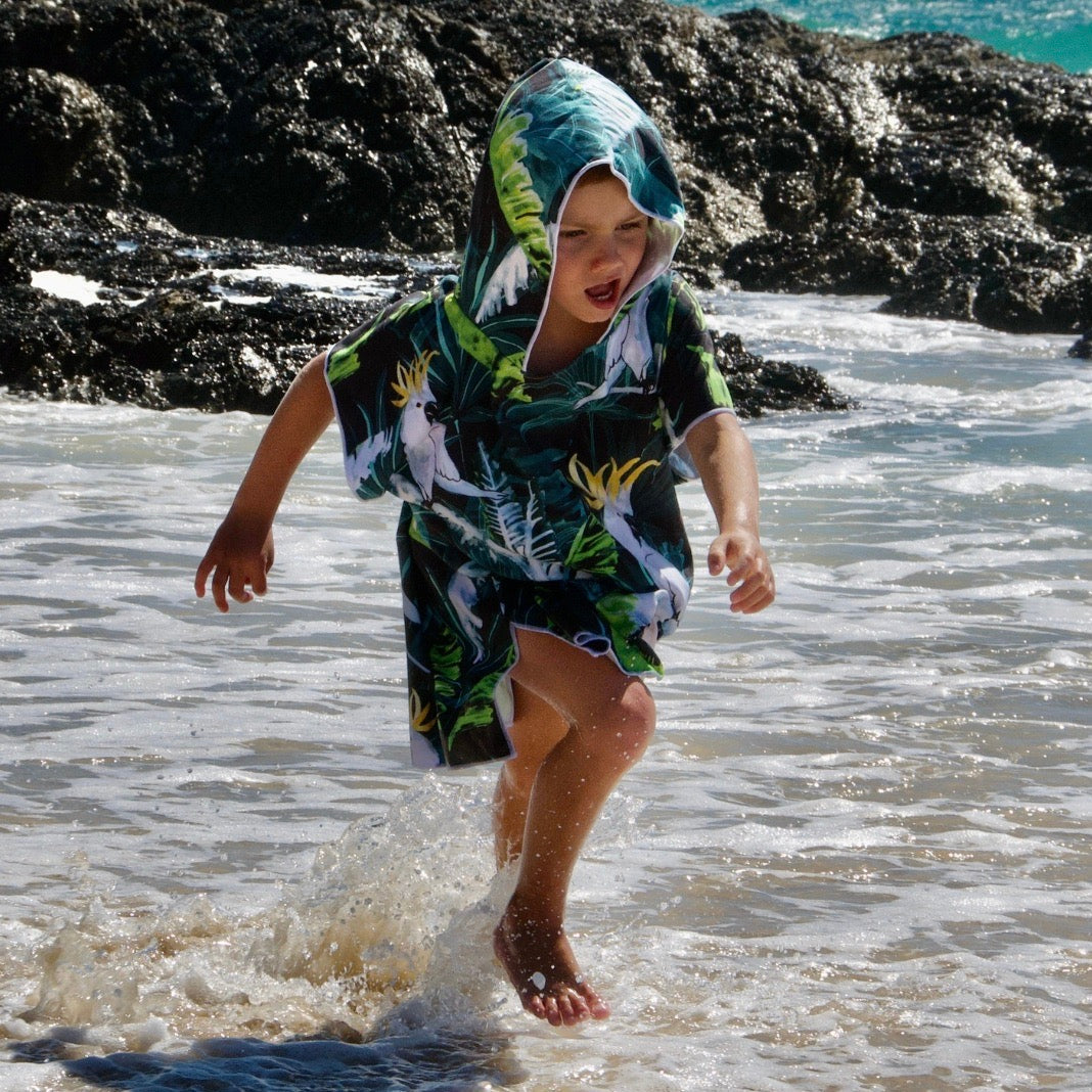 Child wearing sand free beach hoodie Bird of Paradise running in the shallows of the beach at Currumbin 