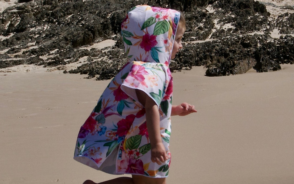 Girl wearing an Island Princess sand free hooded towel running along Currumbin Beach near elephant rock