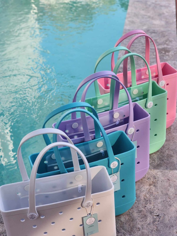 Five silicone bags sitting beside a swimming pool colours white, blue, purple, green and pink