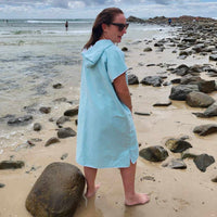 Adult Model in Aqua Lagoon Sand-Free Hoodie (One Size Fits All): [Standing relaxed] on Hastings Point Beach, NSW. This revised alt text clarifies:  Action: The adult is standing in a relaxed pose. Clothing: They are wearing the Aqua Lagoon Sand-Free Hoodie (One Size Fits All). Location: The location is still specified as Hastings Point Beach, NSW.