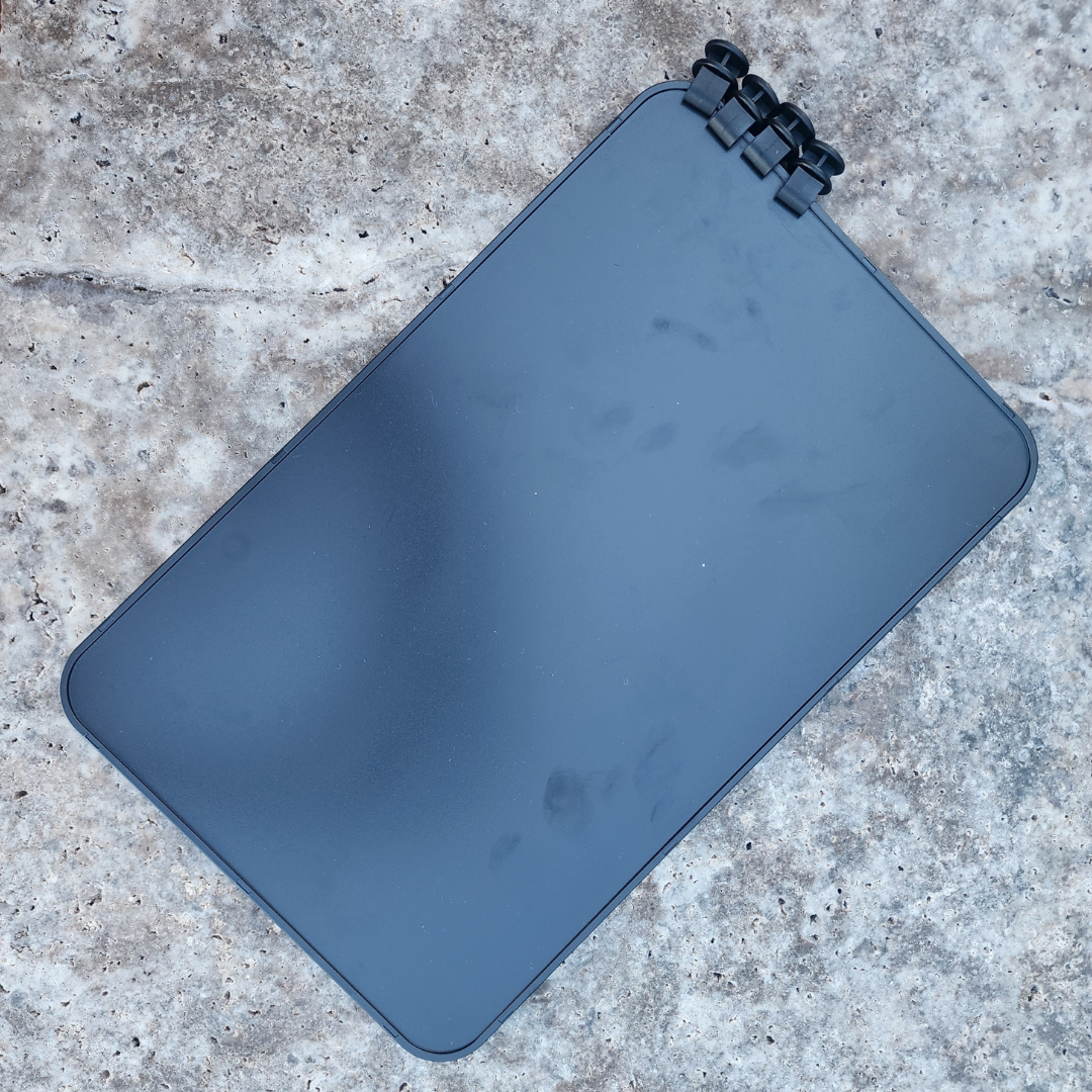 Black rectangular divider for hauler bags with a black clip on a concrete surface