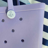 Coral Cove Silicone Bag with Sandi Toes Logo: Everyday Essentials in Style. [Durable coral cove purple silicone bag displays the Sandi Toes logo, ideal for carrying your essentials with a touch of beach flair.]