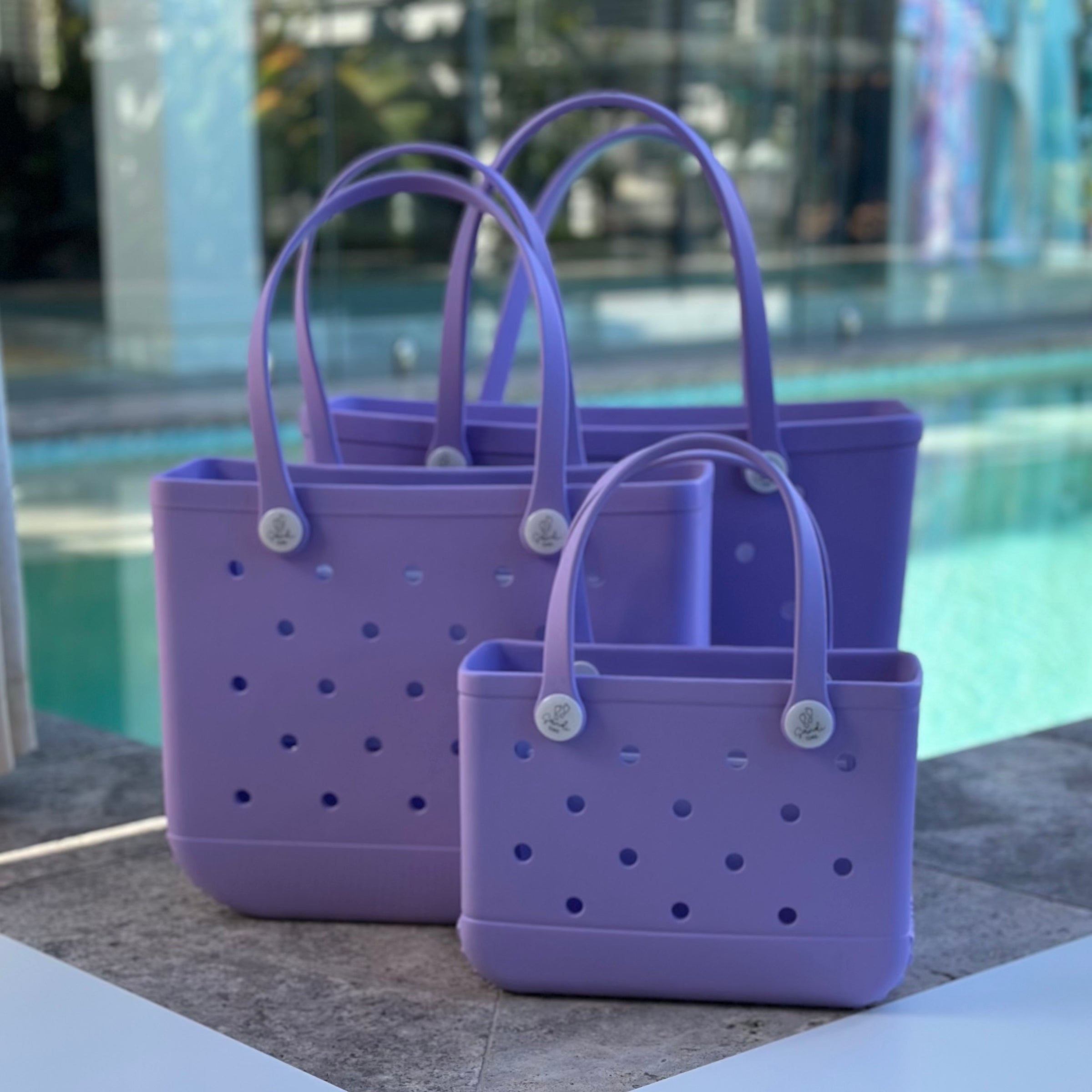 * "All three Coral Cove EVA silicone beach tote bags front view The Hauler, The Everyday and The Mini, showing size, Sandi Toes buttons, and sturdy handles"