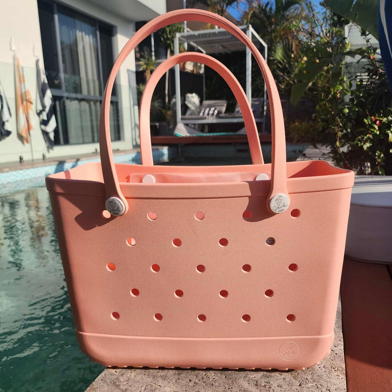 Peach Sunset Spritz EVA Silicone tote bag with on a ledge by a pool